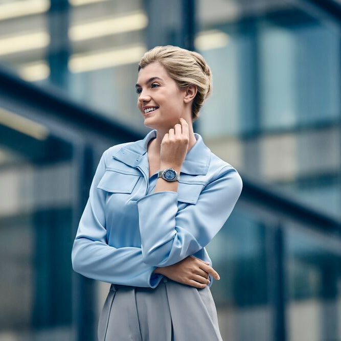 Woman in a light blue jacket standing in front of a modern building